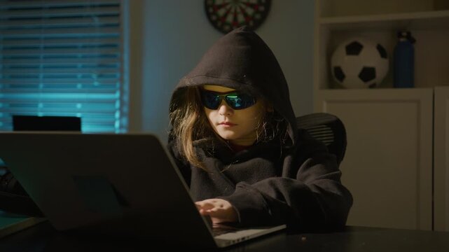 Child hacker with laptop. Hacker kid typing fast on laptop. Kid hacker focused on laptop work. Child hack game on laptop.