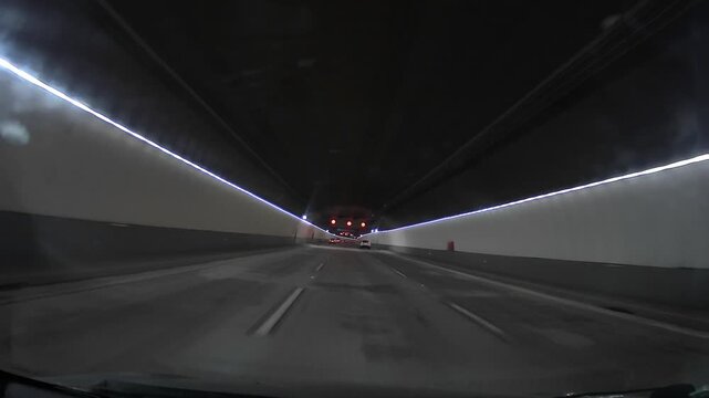 Point of view driving through a modern three-lane underground highway tunnel. Clean urban infrastructure, symmetrical lanes, artificial lighting and smooth forward motion create a contemporary city tr
