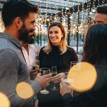 Friends gather to celebrate with drinks at a lively evening party under string lights