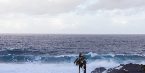 A giant wave crashes against the cliff as it approaches the shore.
