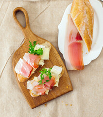 Tasty sandwich slices with ham and cheese on wooden board