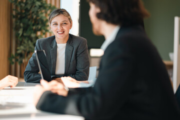 Professional business team having meeting discussing corporate strategy and project results using laptop in modern city environment showing teamwork leadership confident collaboration spirit