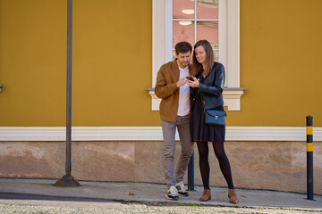 Couple looking at smartphone near yellow building wall