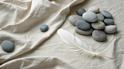 Gathering of smooth stones and a white feather on a light fabric surface