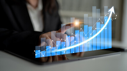 Business professional interacts with a digital chart on a tablet, highlighting financial growth and investment trends in a modern and innovative workspace. Scalp