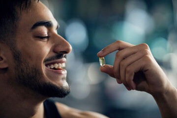 Best Multivitamins. Portrait Of Handsome Young Arab Guy Holding Supplement Capsule With Fingers,...