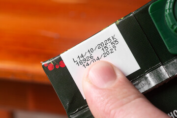 A man checks the production date and expiration date on a juice pack.