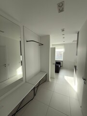 Modern minimalist apartment hallway with mirror, bench and natural light