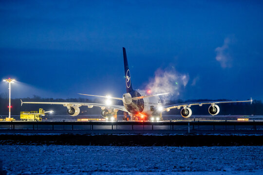 Ein Airbus A380 der Lufthansa wird am Flughafen M&uuml;nchen bei Dunkelheit und Minustemperaturen enteist. Im Hintergrund ist ein Enteisungsfahrzeug im Einsatz. 