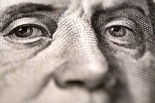 Detail of Benjamin Franklin's face on a US $100 bill. Franklin was one of the Founding Fathers of the United States, editor and signatory of the Declaration of Independence, and first Postmaster