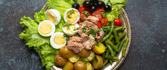 Nicoise salad with tuna, olives, green beans, tomatoes and quail eggs on a bed of lettuce