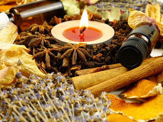 Dried herbs, flowers, bottles with essential oil, spice, orange peesl and scented candle, side view, background. Ingredients for air freshening and relaxation.
 