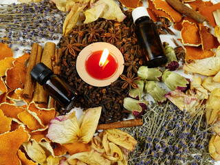 Dried herbs, flowers, bottles with essential oil, spice, orange peesl and scented candle, top view, background. Ingredients for air freshening and relaxation.
 