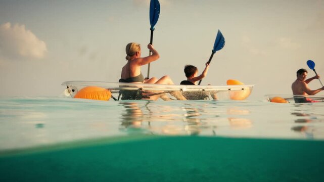 Family clear bottom kayaking in beautiful tropical ocean at sunset