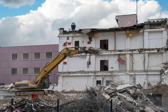 Yellow excavator dismantling building at demolition site. Yellow excavator dismantling building at demolition site - Powered by Adobe
