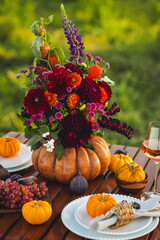 Elegant autumn decoration. Private wedding party for two, table set with floral decor, pumpkins, wine in field or meadow. Fall vibes, sunset, golden hour. Romantic surprise, marriage proposal