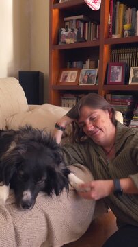A woman is petting a black and white dog on a couch