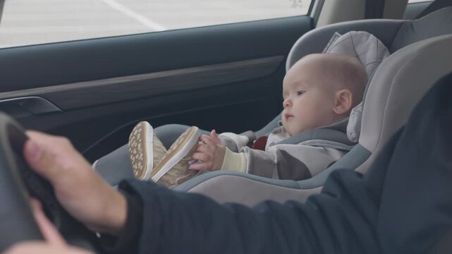 caucasian infant in car seat in modern car interior. Daylight through window during short road trip. Secure harness. concept of baby safety in a child seat