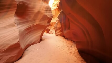 An immersive, smooth pov tracking video moving through a narrow, winding slot canyon with vibrant orange sandstone, ethereal sunbeams, and golden hour glow, concept of natural adventure