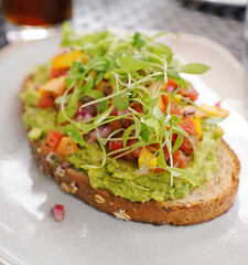 Gourmet avocado toast on artisinal bread with pickled mango, onions and microgreens