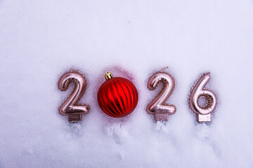Festive New Year 2026 composition on snow with a red Christmas ornament replacing zero, creating a bright holiday accent