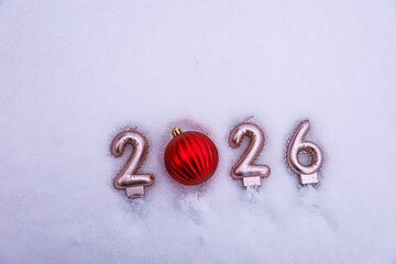 New Year 2026 written on snow with a red Christmas bauble instead of zero, leaving copy space for holiday messages or greetings