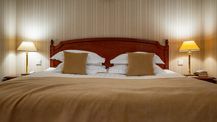 Large comfortable double bed with white pillows and beige blanket in a luxury hotel room