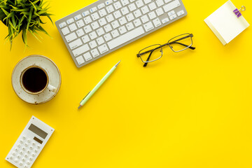 Home office workspace with computer keyboard and cup of coffee on yellow background, top view. Education online. Tabletop of freelancer.