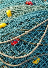 Texture and detail of a large, heavy fishing net, featuring thick marine ropes, durable nylon mesh, and colorful plastic buoys used for flotation, knot, thread, commercial