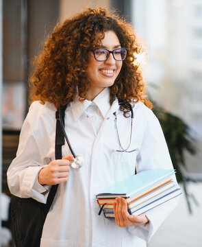 Female medical student smiling wearing lab coat and books