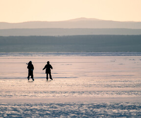 silhouette of people skating on a frozen lake