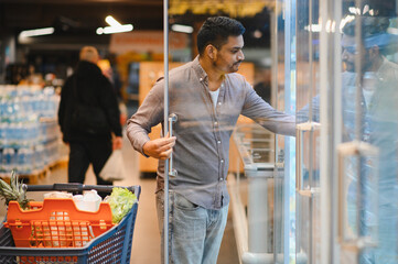 Man shopping for groceries in a supermarket freezer aisle
