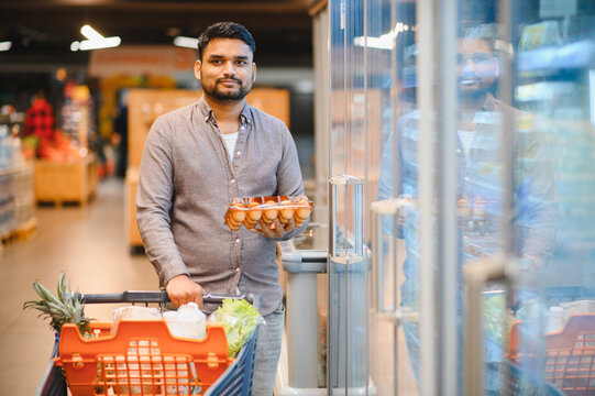 Man shopping for groceries holding eggs in supermarket