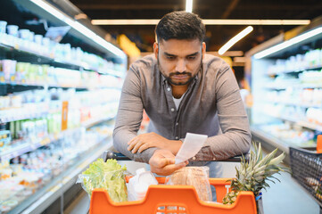 Man checking grocery prices on receipt facing inflation