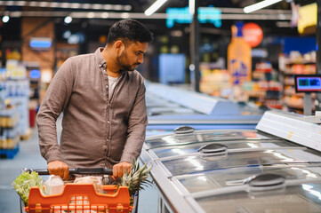 Man shopping for frozen food in supermarket aisle