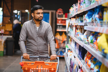 Man pushing shopping cart in supermarket aisle
