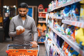 Man holding product while pushing shopping cart in supermarket