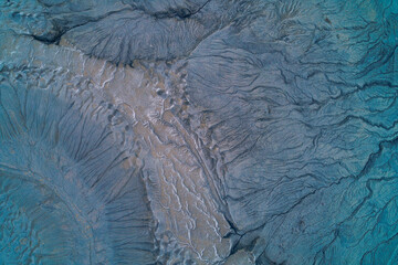 Abstract dark blue mudflow texture with dendritic erosion channels and wet clay soil, cold industrial wasteland background aerial top down view
