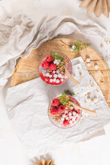 An overhead shot of two glasses of layered raspberry and chia seed pudding with fresh raspberries...