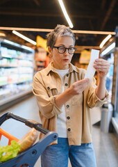 Woman checking grocery shopping receipt managing budget