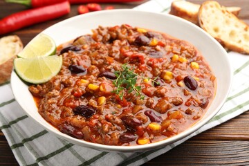 Delicious chili con carne served on wooden table, closeup
