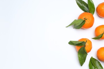 Ripe tangerines and green leaves on white background, flat lay. Space for text