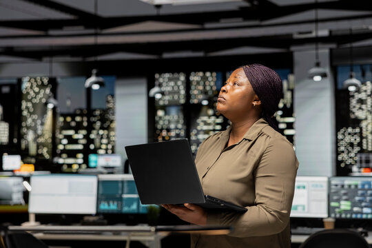 Businesswoman does critical thinking and proofreading documents before transcribing information on notebook, standing in the office at night time. Documenting important ideas.