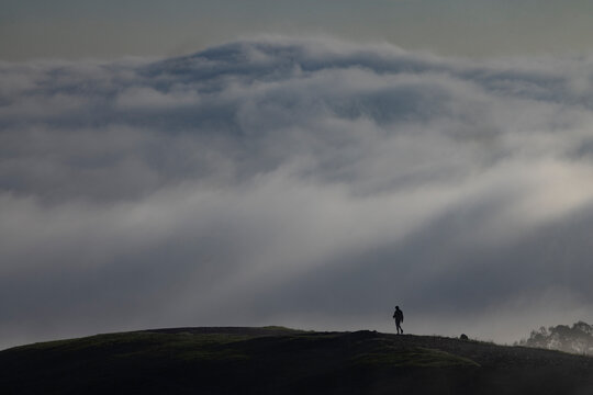 Very small person on cloudy hilltop