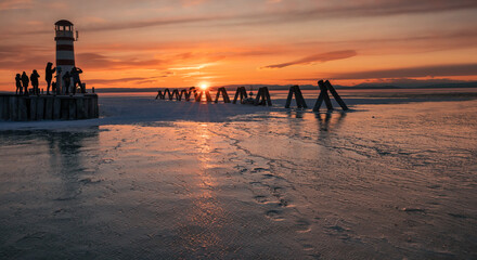 frozen Neusiedl lake in Austria with lighthouse at sunset