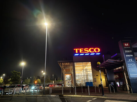 Tesco supermarket night scene in SalfordUK with bright neon sign and busy storefront