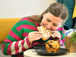 A girl sits at a table in a cafe and eats her breakfast