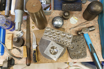 Overhead view of various metalworking tools and specialized jewelry forming equipment.