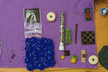 Various beadwork supplies and handmade jewelry elements arranged on a purple felt mat.
