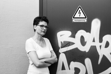 Confident businesswoman standing with crossed arms against urban wall
